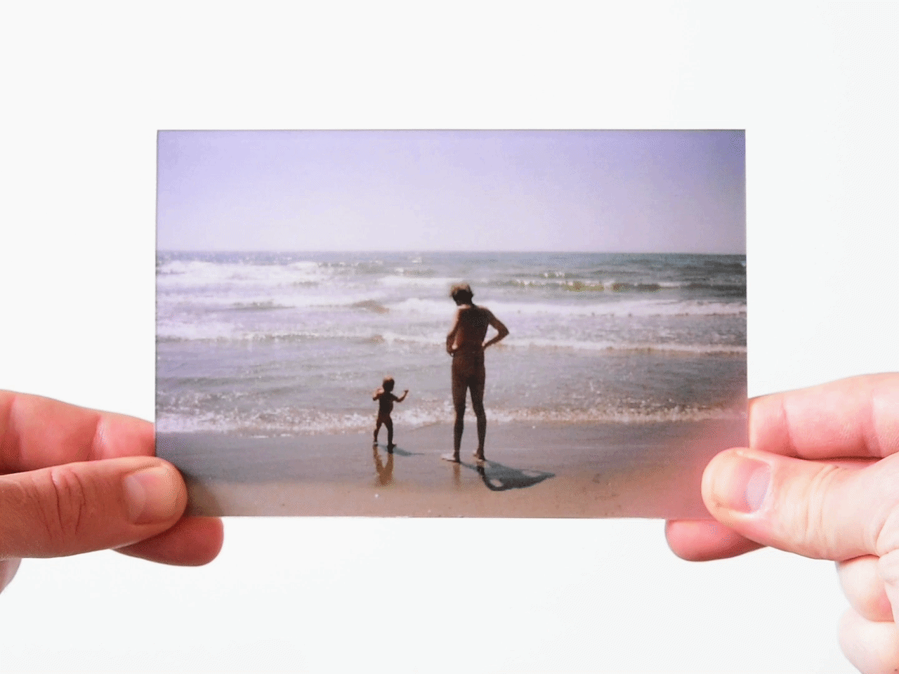 Childhood photo of father and child at the beach with ocean waves in the background