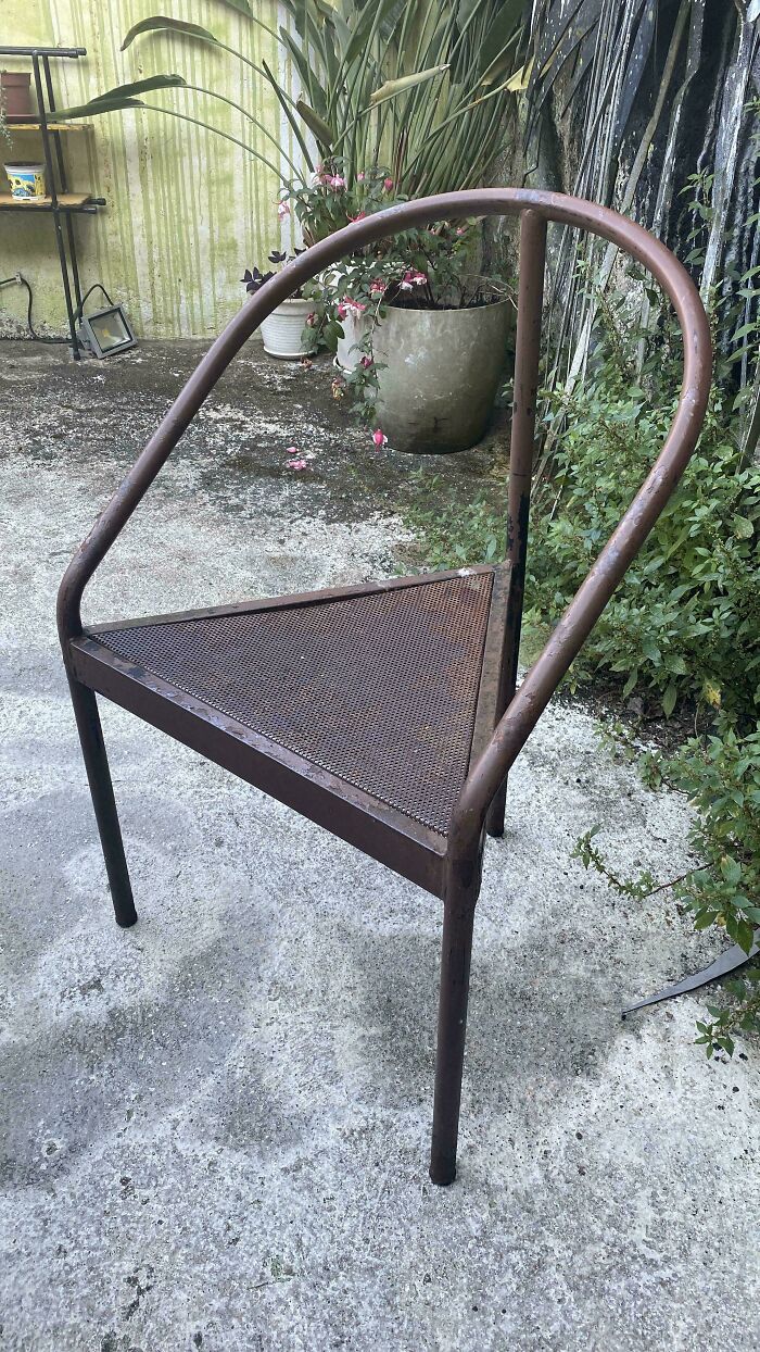 A rusty, triangular chair with an uncomfortable design, illustrating a practical design fail.