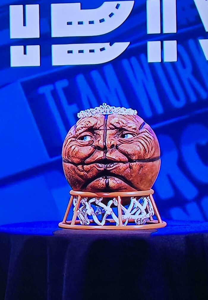 A truly bizarre trophy resembling an old, sad face with a crown, on a blue background.