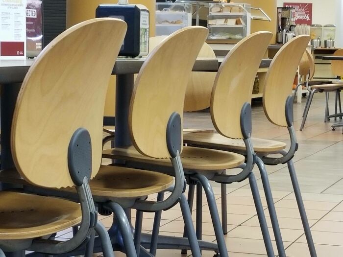 Chairs with unusual, surfboard-like backs in a cafeteria, perhaps near where forbidden foods might be served.
