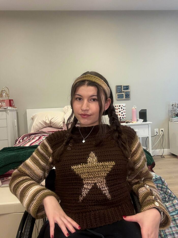 Person wearing a crochet sweater with a star design sitting in a room