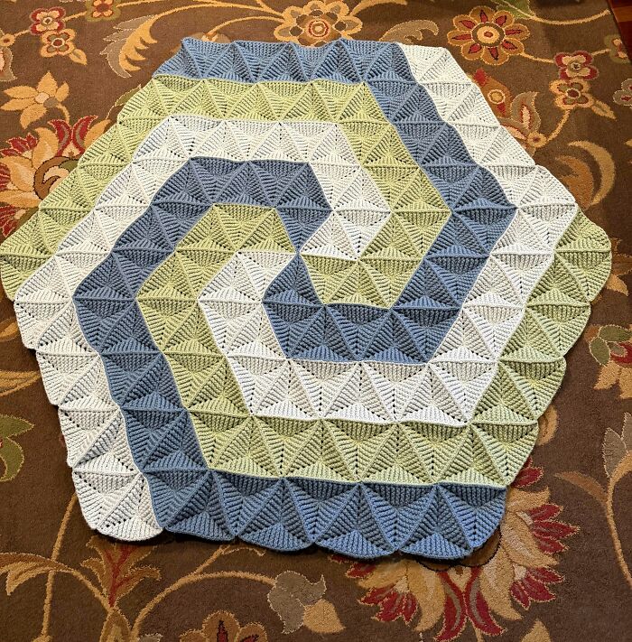 Crocheted hexagonal blanket with geometric pattern in blue, white, and green colors