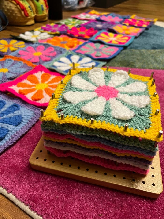 Colorful crocheted flower squares stacked on a blocking board for crochet project