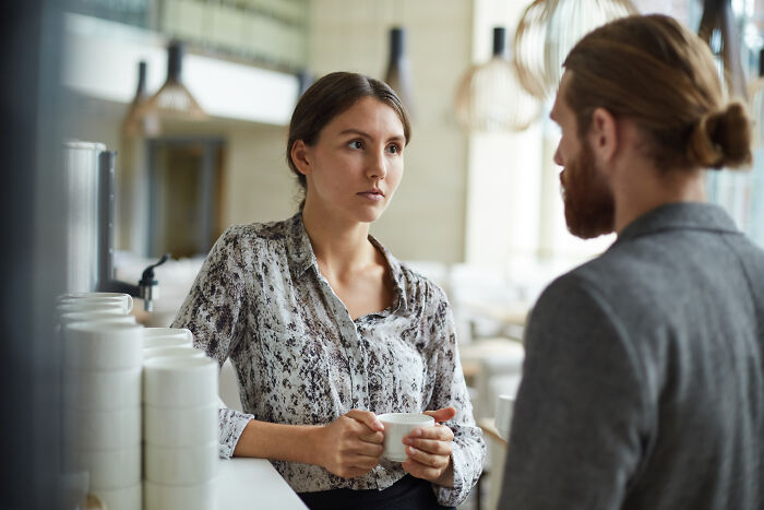 Woman holding cup listening during clever insult conversation