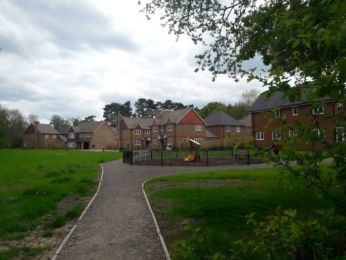 A small playground area nestled between modern houses and green fields, a common playground setup.