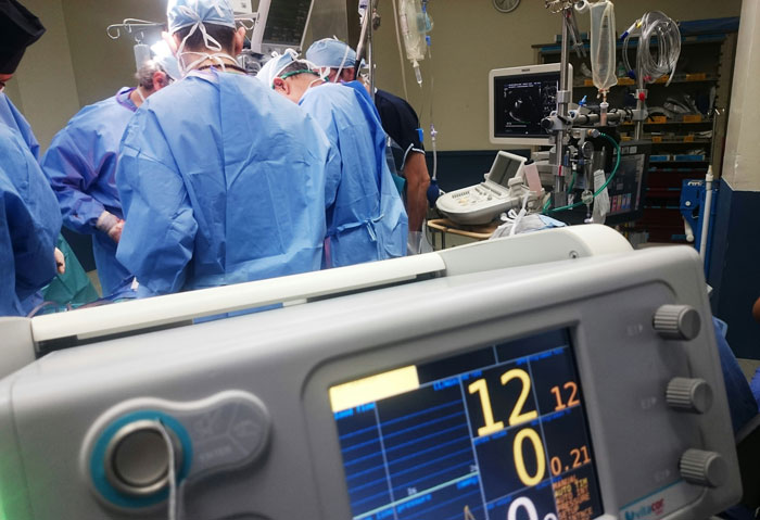 Medical team performing surgery with heart monitoring equipment
