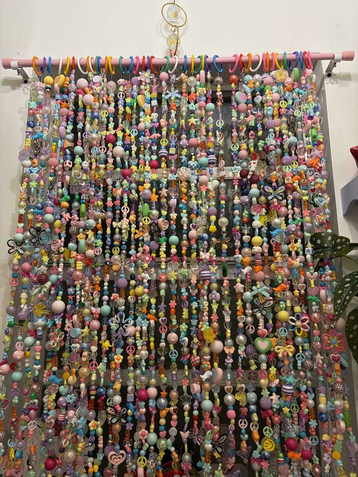 Colorful beaded curtain with peace signs and butterfly charms on pink rod