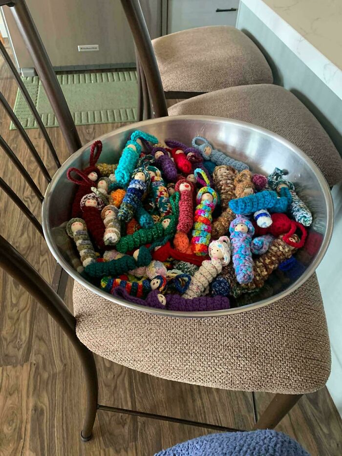 Metal bowl filled with small crocheted dolls on kitchen counter