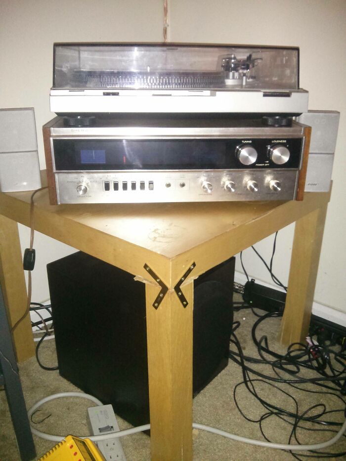 An audio setup on a wobbly, poorly constructed table, showcasing DIY fails.