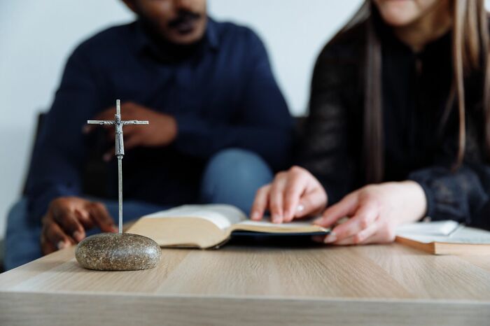 A couple sits at a table with an open Bible and a cross, illustrating a peaceful scene before an airline journey.