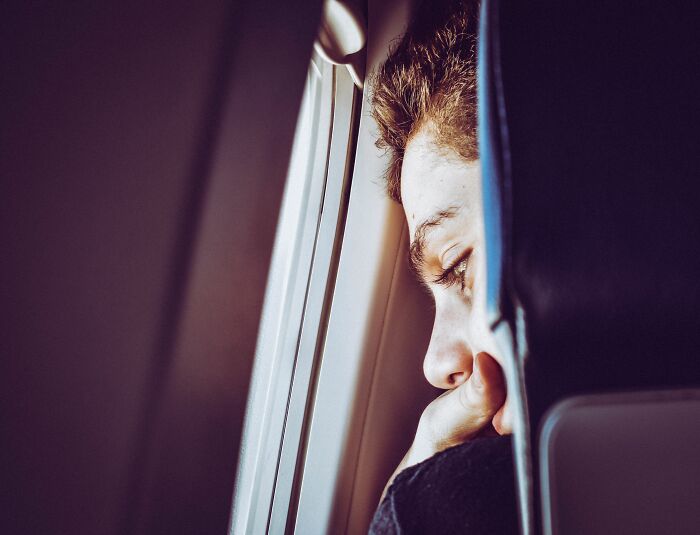 A man looking out an airplane window, reflecting on entitled people who got a reality check at 30,000 feet.