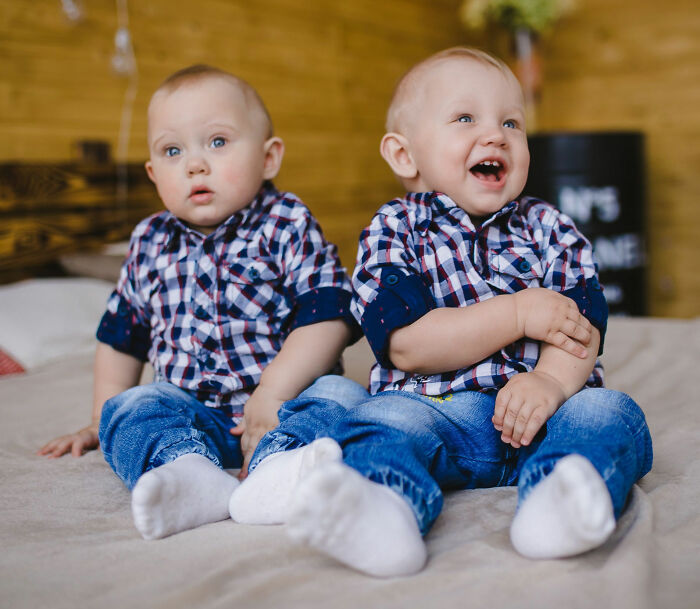 Two young children, possibly twins, dressed in matching plaid shirts and jeans, looking at the camera.