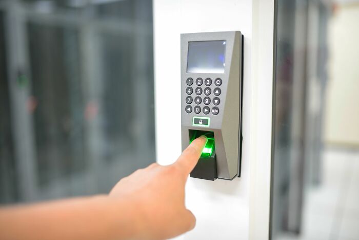 A hand pressing a finger on a biometric security scanner, a safety tip for women living alone.