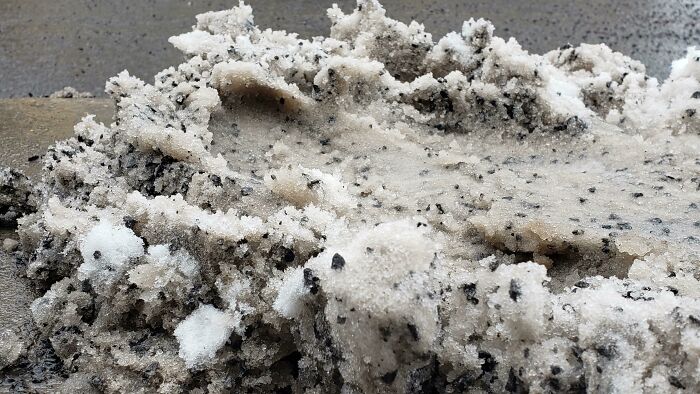 A close-up of dirty, melting snow mixed with black grit. These are forbidden foods.