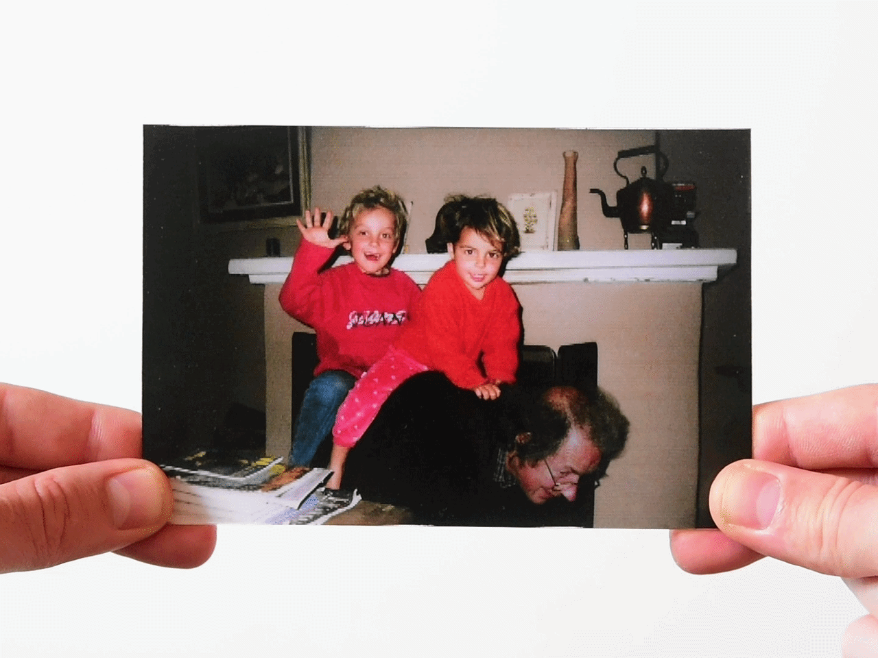 Child riding on father's back waving, with another child sitting next to them