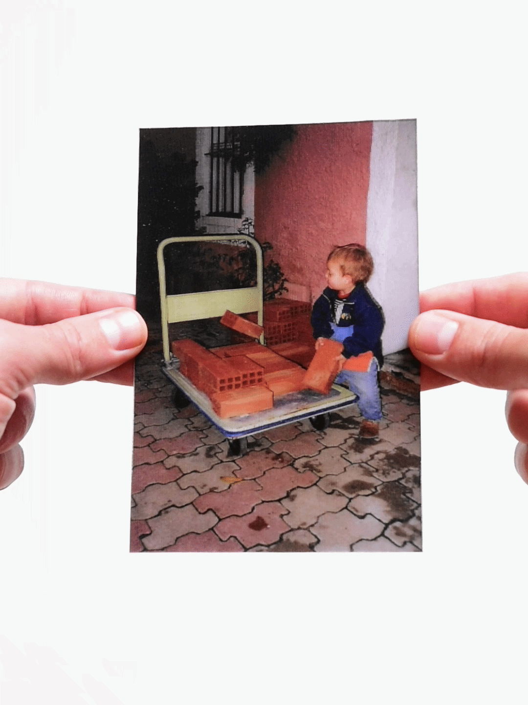 Childhood photo of a boy holding bricks on a cart outdoors