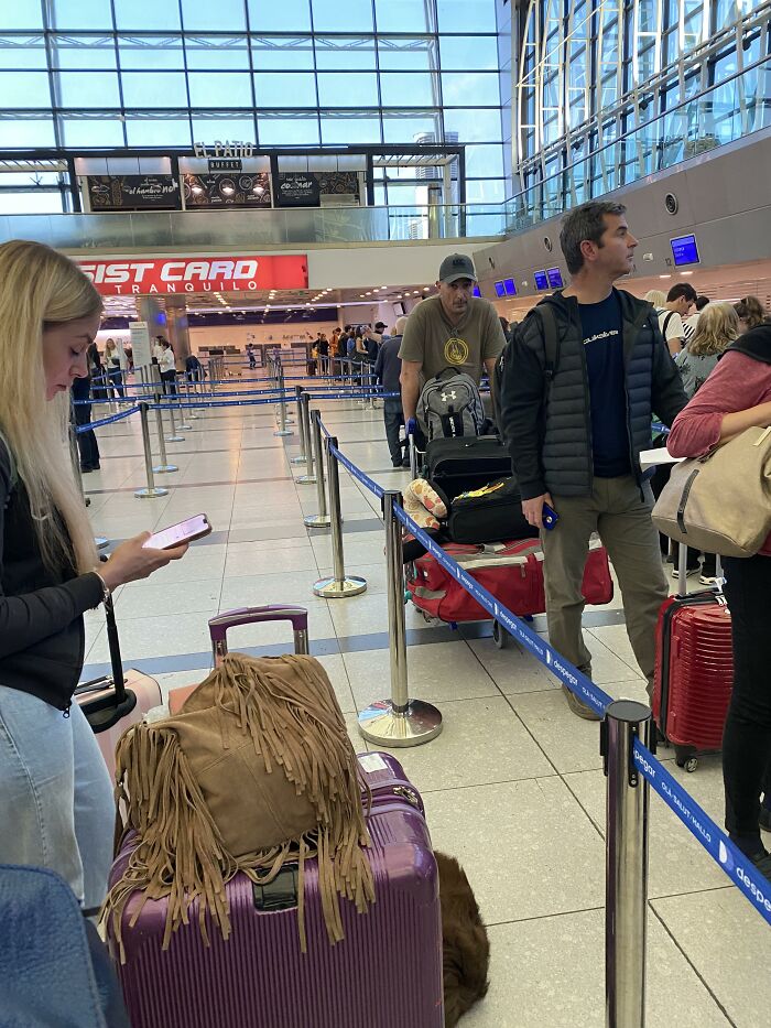 A woman at an airport check-in counter in a line, showing entitled people getting a reality check.