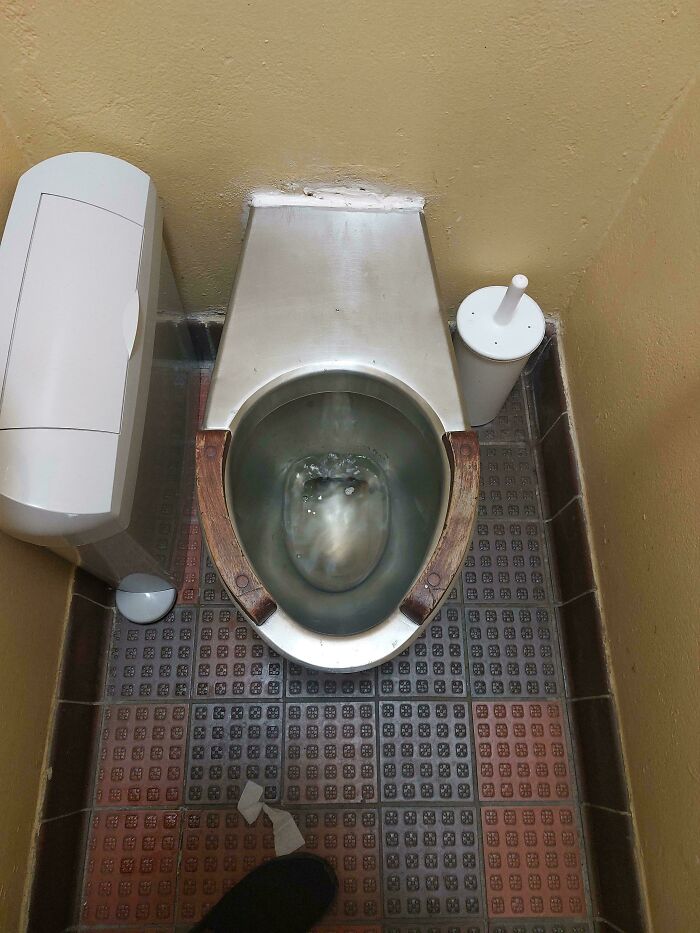 A hilariously unhinged design fail: a toilet in a cramped space, making it difficult to use, highlighting poor planning.