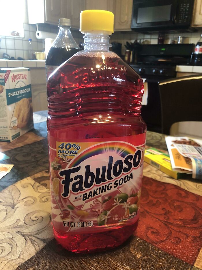 A large bottle of red Fabuloso cleaner with baking soda, mistakenly placed on a table like a forbidden food.