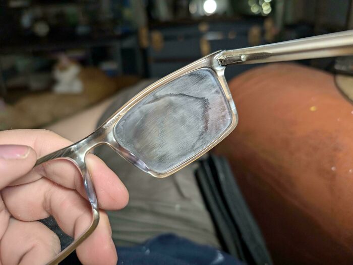 A close-up of eyeglasses with severely scratched and cloudy lenses, a clear DIY fail.