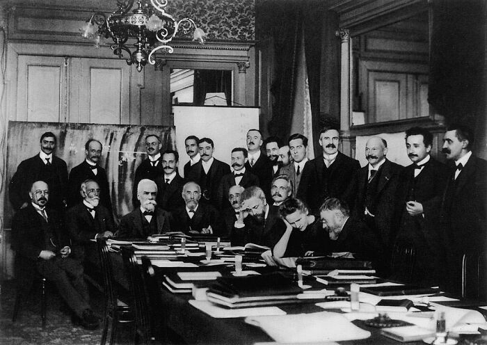 Distinguished men and a few women gathered around a large table, a significant moment in Women In History.