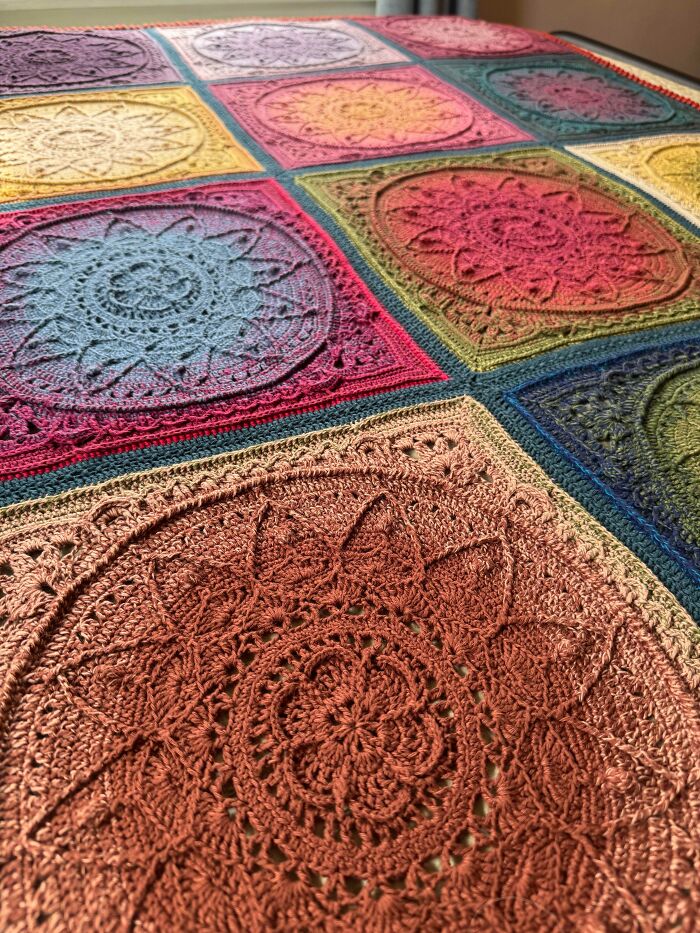 Multicolored crocheted blanket featuring intricate mandala-inspired square patterns