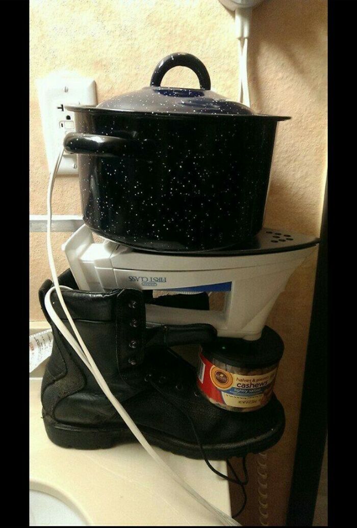 A makeshift cooking setup with a pot balanced on an iron, supported by a boot and can, a funny DIY fail.
