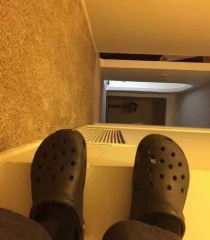 A low-angle shot of black Crocs at the top of a flight of stairs, conveying a sense of precarious online lies.