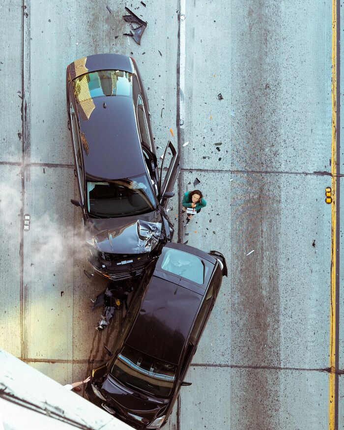 Perfectly timed street photo by Jeremy Paige showing an aerial view of two crashed cars on a street.