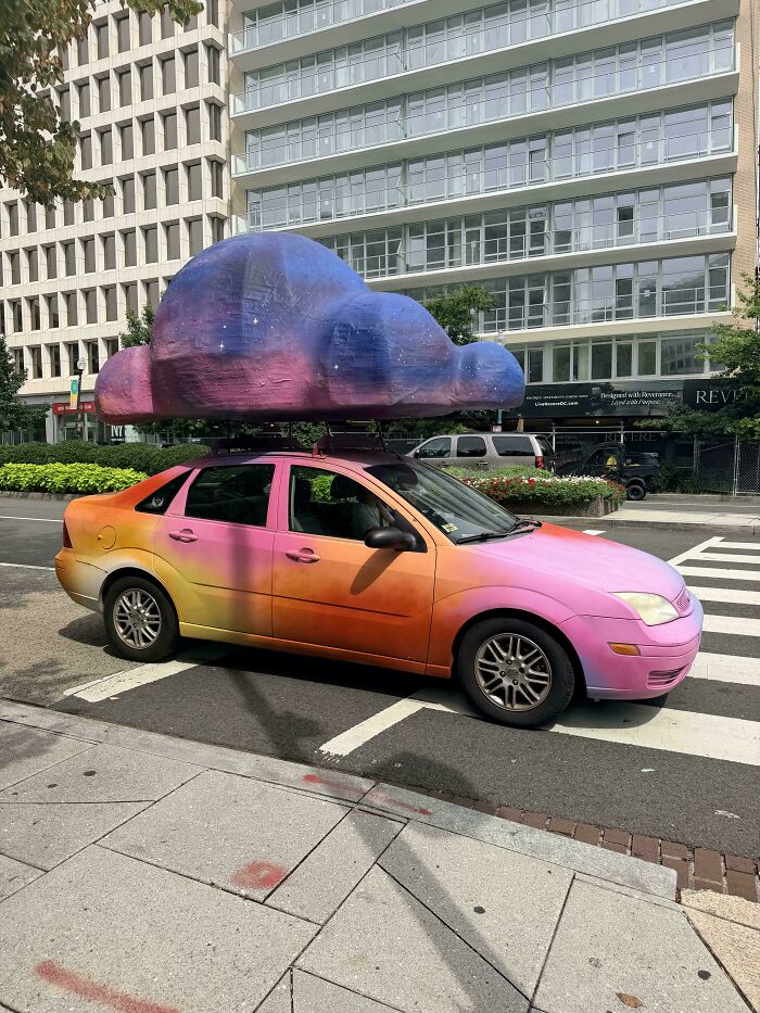 Car painted in gradient colors with large cloud sculpture on roof