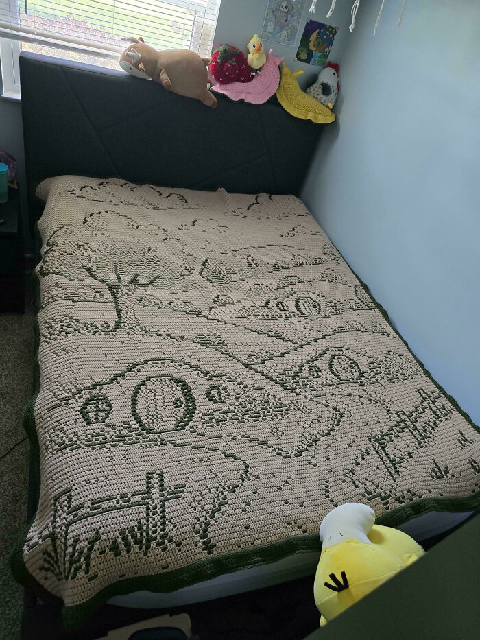Crocheted landscape blanket with cars and trees on a bed in a bedroom