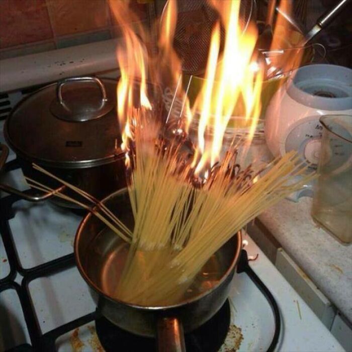 A pot of spaghetti on a stove, engulfed in flames, illustrating a major kitchen fail.
