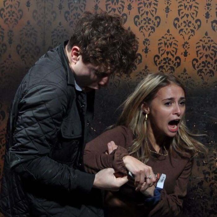 A frightened young woman screaming in fear next to her friend in a haunted house photo