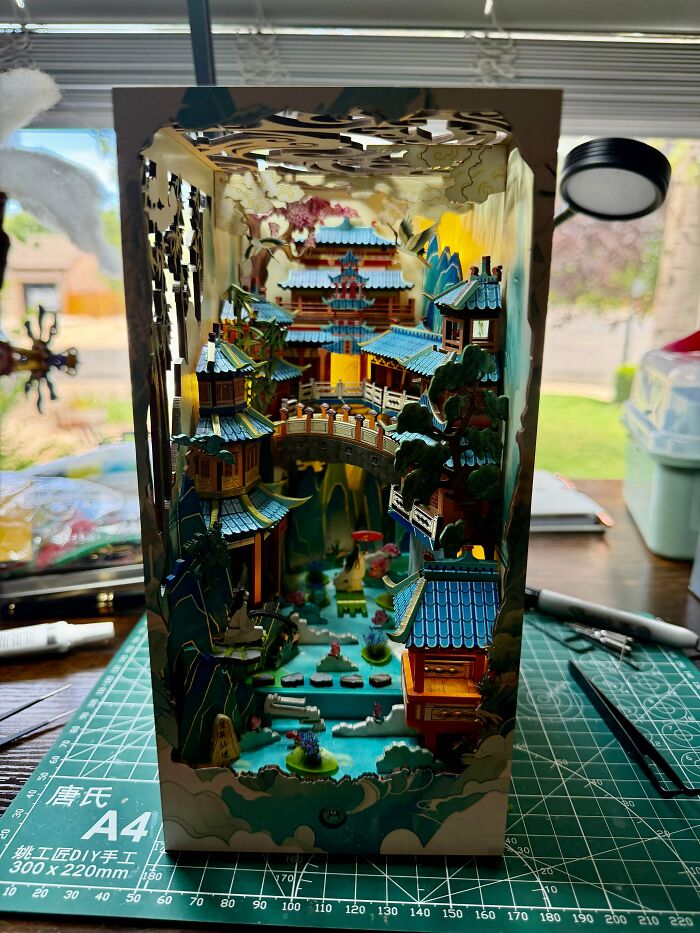 An intricate book nook featuring a Chinese-style palace with bridges and blue rooftops