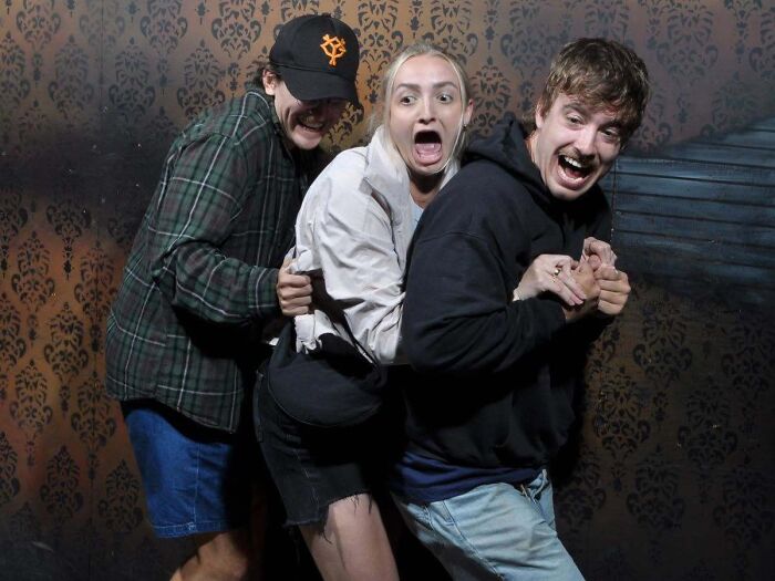 Scared group of friends clinging to each other in a haunted house photo reaction