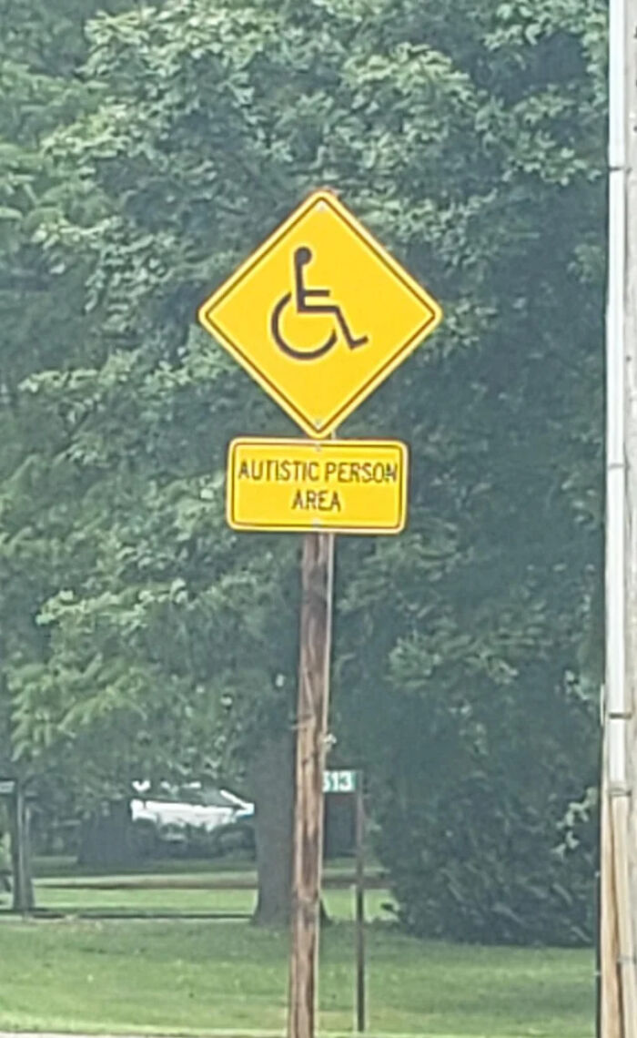 An unusual street sign reading Autistic Person Area with a wheelchair symbol, showing a sign mistake.