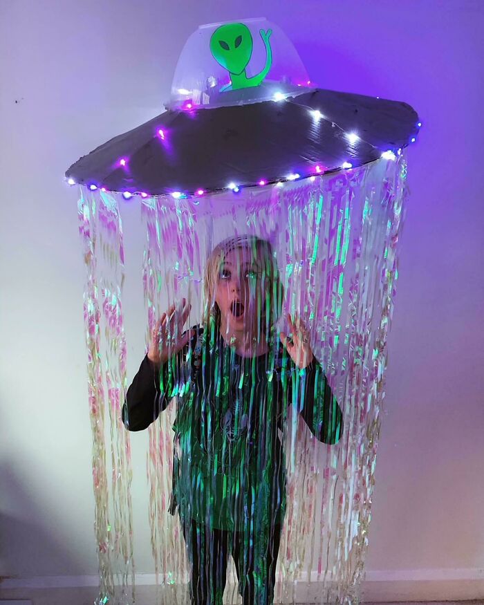 A kid wearing a glowing UFO abducting alien creative Kids Halloween Costume with tinsel.