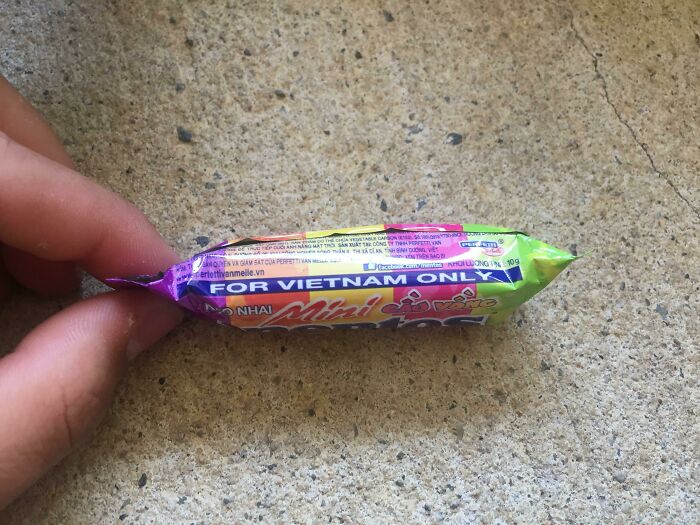 Hand holding a tiny candy wrapper with misaligned printing as an example of bad packaging fails.