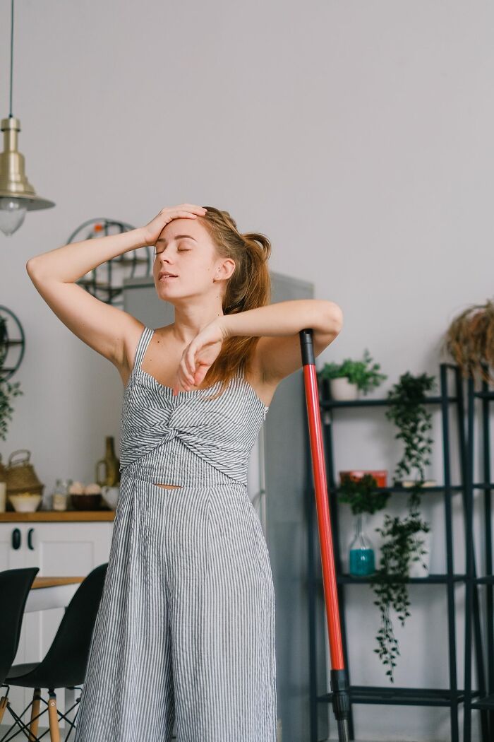 A tired woman rests on a mop in her kitchen, showing the exhaustion that can make marriages collapsed