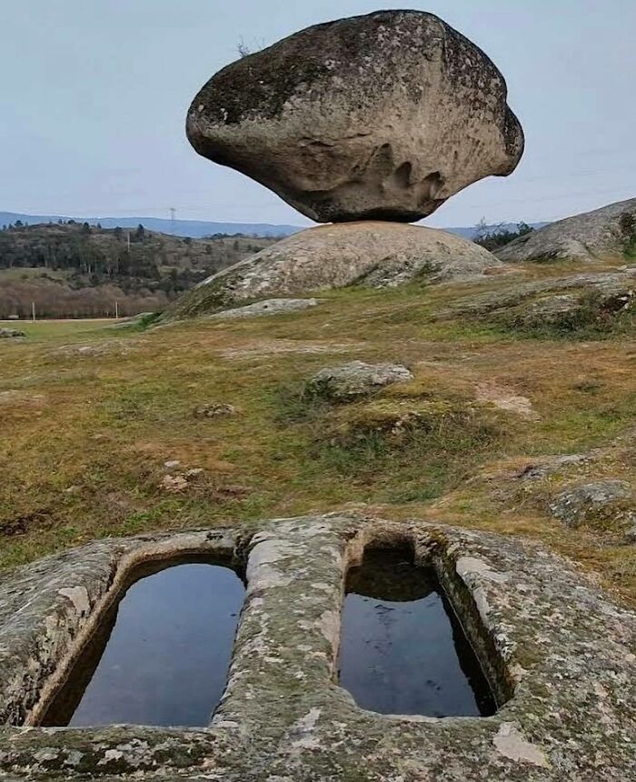 A balancing rock formation over ancient graves in a field showcasing interesting facts about the past.