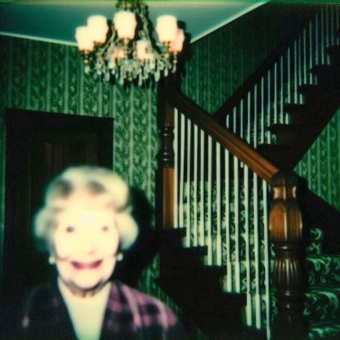 Eerie blurry portrait of a smiling woman near a staircase, resembling a horror movie still