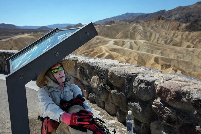 Hiker taking shade under a sign, captured in photos for the last time.