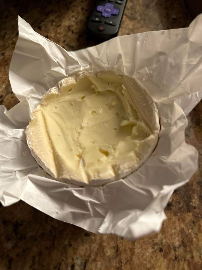 A round of soft cheese with the middle scooped out, showcasing funny quirks of a husband.