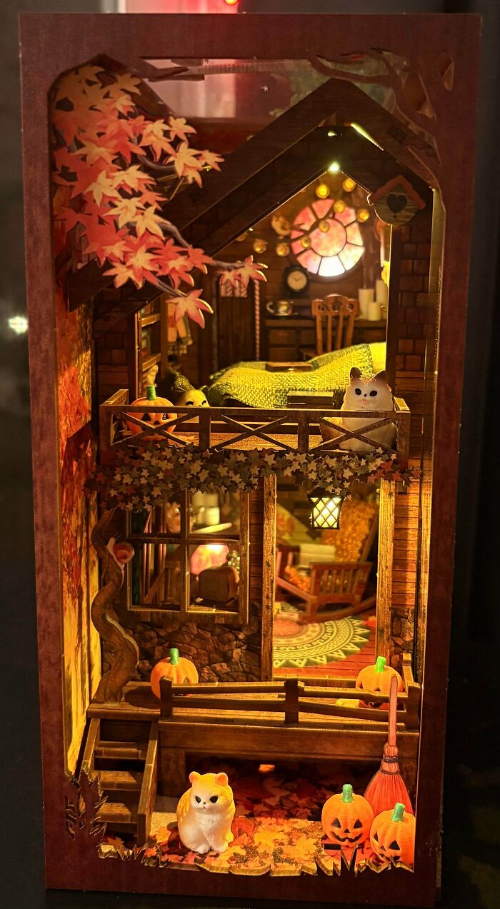 An autumn-themed DIY book nook miniature house complete with pumpkins and cats.