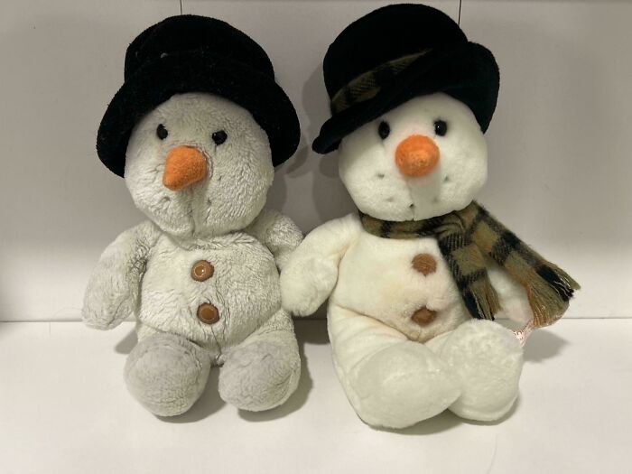 Two snowman plush toys, charming thrift store finds, sitting side-by-side on a white shelf