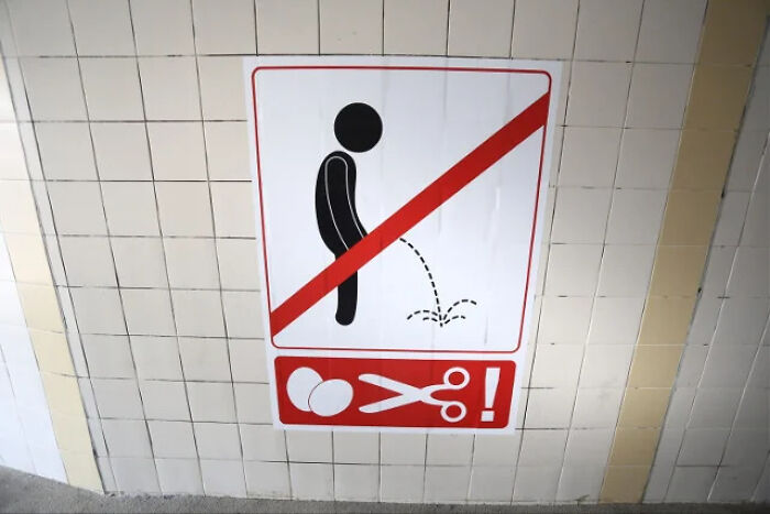 A hilarious no-peeing sign on a tiled wall threatening scissors, showing signs that look like mistakes