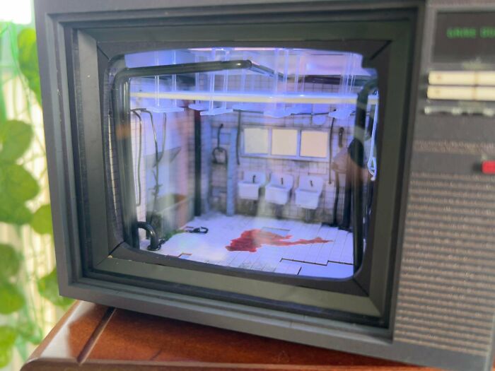 An eerie television-shaped book nook depicting a bloody bathroom crime scene with glowing blue lights.