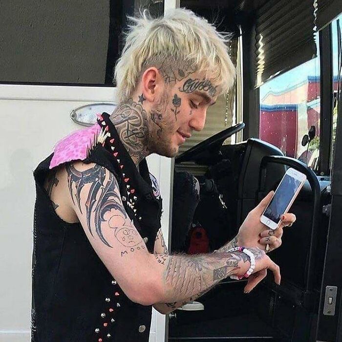 Lil Peep looking at his smartphone near a vehicle, captured in photo for the last time in his life
