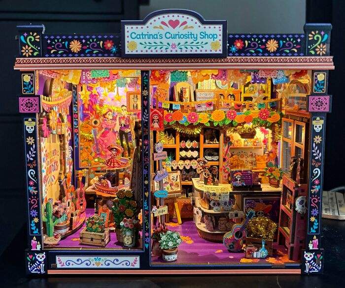 A colorful Day of the D**d themed book nook with miniature skeleton figurines and vibrant decorations.