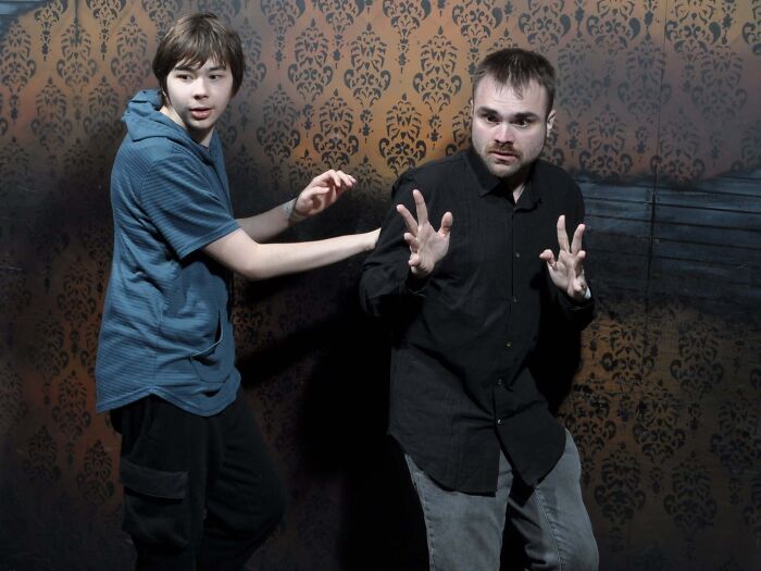 Two startled young men jumping back in fear in funny haunted house photos inside an attraction.